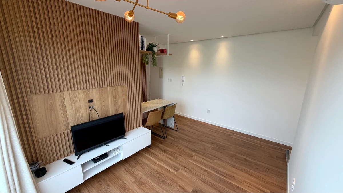 Sala do apartamento com painel de madeira e móveis planejados.